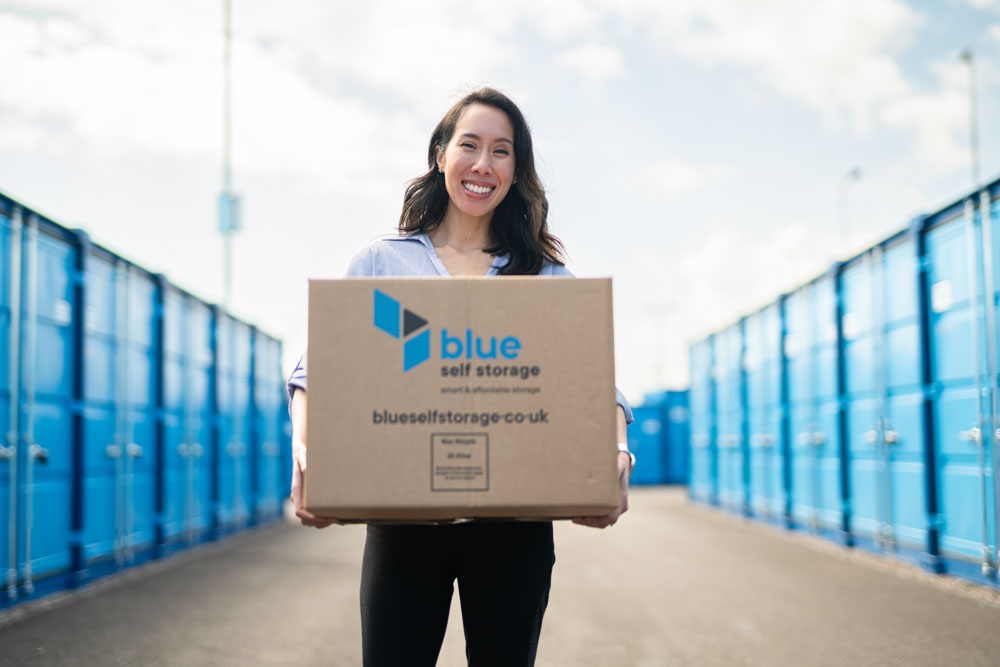 Woman holding a blue self storage box at a blue self storage facility